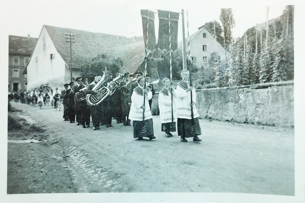 Ansicht der Haupstrasse in der Nähe der heutigen Bushaltestelle. Anlass des Umzugs war die Glockenweihe der Geißlinger Kirche.